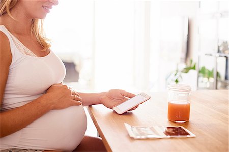 simsearch:614-08726746,k - Cropped shot of pregnant young woman at desk looking at smartphone and ultrasound pictures Foto de stock - Royalty Free Premium, Número: 649-09061438