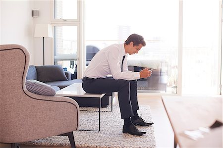 simsearch:649-09061407,k - Businessman sitting on coffee table looking at smartphone Photographie de stock - Premium Libres de Droits, Code: 649-09061442