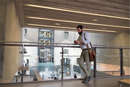 simsearch:649-09061548,k - Man on mezzanine in office building texting on smartphone Stock Photo - Premium Royalty-Free, Code: 649-09061545