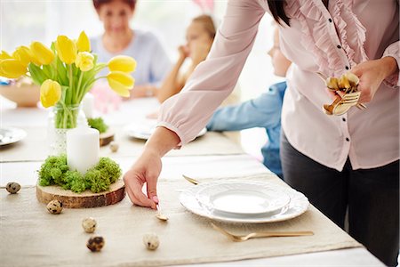 family on dining table photography - Woman and family preparing place settings at easter dining table Stock Photo - Premium Royalty-Free, Code: 649-09061685