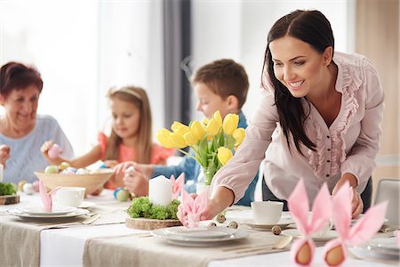 Woman and family preparing place settings at easter dining table Foto de stock - Sin royalties Premium, Código: 649-09061683