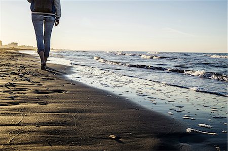 Waist down view of barefooted woman strolling along water's edge on beach, Riccione, Emilia-Romagna, Italy Photographie de stock - Premium Libres de Droits, Code: 649-09061889