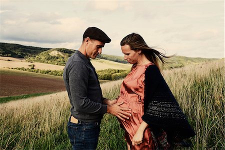 Romantic man with hands on pregnant wife's stomach on hillside Foto de stock - Royalty Free Premium, Número: 649-09061898