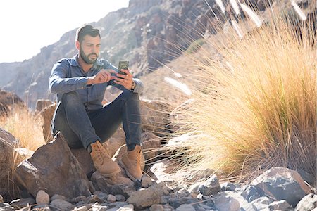 simsearch:649-09156185,k - Young male hiker sitting on boulder looking at smartphone in valley, Las Palmas, Canary Islands, Spain Foto de stock - Royalty Free Premium, Número: 649-09061922