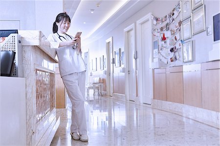 Doctor in hospital corridor using smartphone Stock Photo - Premium Royalty-Free, Code: 649-09061947