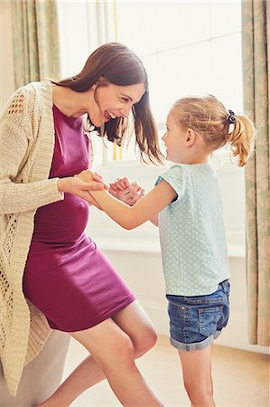 Laughing pregnant woman playing with daughter in living room Stock Photo - Premium Royalty-Free, Code: 649-09077939
