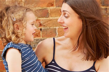 Cute girl and laughing mother by brick wall Stock Photo - Premium Royalty-Free, Code: 649-09077946
