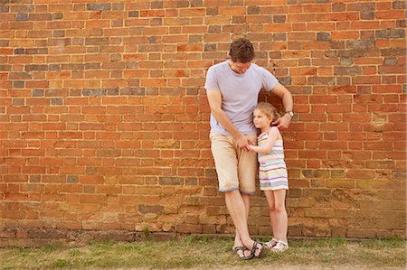 Girl and father leaning against brick wall Stock Photo - Premium Royalty-Free, Code: 649-09077952