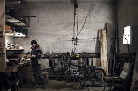 Mechanic looking at workbench in workshop with dismantled vintage motorcycle Photographie de stock - Premium Libres de Droits, Code: 649-09077964