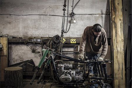 Mechanic inspecting dismantled vintage motorcycle in workshop Photographie de stock - Premium Libres de Droits, Code: 649-09077974