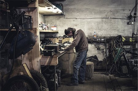 Mechanic working at bench with dismantled vintage motorcycle in workshop Stock Photo - Premium Royalty-Free, Code: 649-09077976