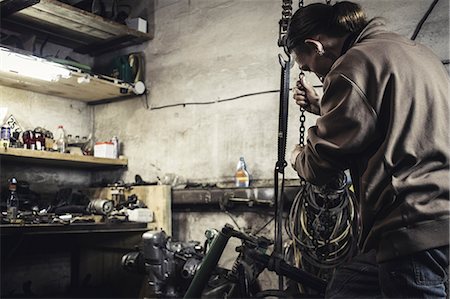 Mechanic hoisting dismantled vintage motorcycle in workshop Photographie de stock - Premium Libres de Droits, Code: 649-09077979