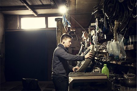 simsearch:6113-06753249,k - Mechanic repairing vintage motorcycle wheel at workshop bench Stock Photo - Premium Royalty-Free, Code: 649-09077972