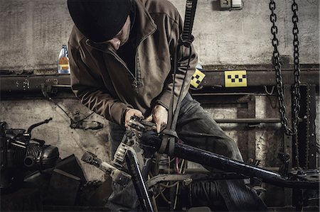 Mechanic repairing dismantled vintage motorcycle in workshop Stock Photo - Premium Royalty-Free, Code: 649-09077981