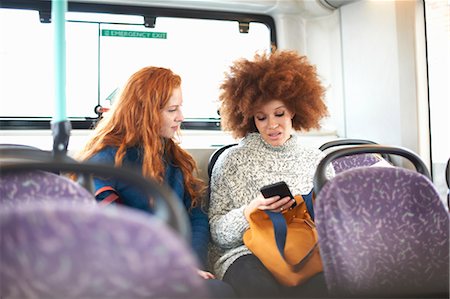 Two young women sitting on bus, looking at smartphone Stock Photo - Premium Royalty-Free, Code: 649-09077998