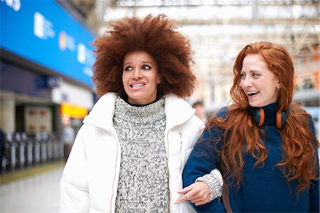 Two young women at train station, walking arm in arm Stock Photo - Premium Royalty-Free, Code: 649-09078016