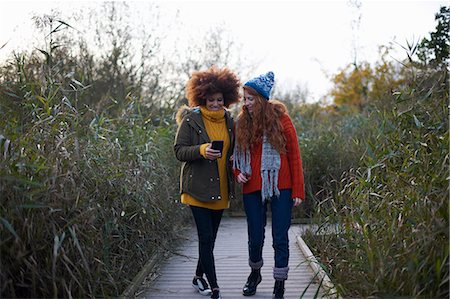 simsearch:649-09078096,k - Friends on walkway in tall grass looking at smartphone Foto de stock - Royalty Free Premium, Número: 649-09078117
