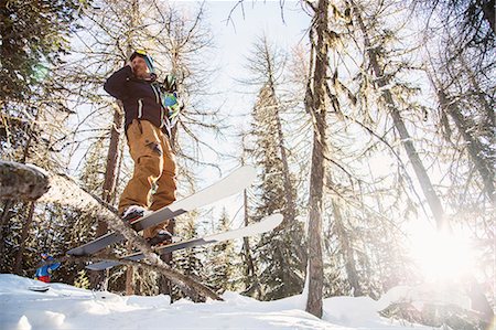 Skier, wearing skis, balancing on tree, low angle view Fotografie stock - Premium Royalty-Free, Codice: 649-09078185