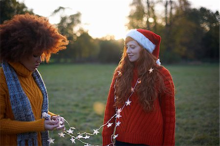 Two young women, in rural setting, young woman wrapped in fairy lights Stock Photo - Premium Royalty-Free, Code: 649-09078225
