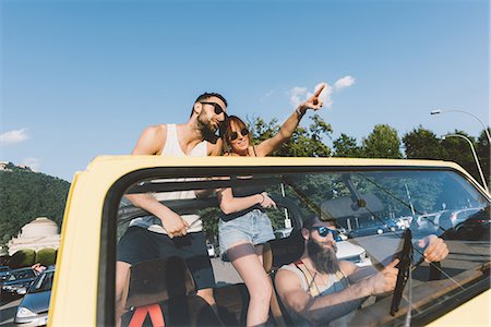 Three young adults driving and pointing on road trip in off road vehicle, Como, Lombardy, Italy Stock Photo - Premium Royalty-Free, Code: 649-09078244