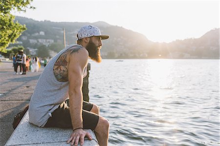 simsearch:649-09078282,k - Young male hipster sitting on wall looking out at lake Como, Lombardy, Italy Stock Photo - Premium Royalty-Free, Code: 649-09078319