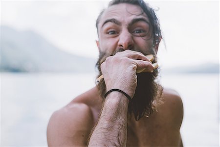 Portrait of male hipster eating sandwich at lake Como, Lombardy, Italy Stock Photo - Premium Royalty-Free, Code: 649-09078311