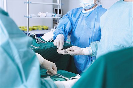 simsearch:649-09078375,k - Over shoulder view of surgeon handed surgical scissors in maternity ward operating theatre Stock Photo - Premium Royalty-Free, Code: 649-09078344