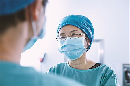 simsearch:649-09078375,k - Over shoulder view of surgical team wearing scrubs having discussion in maternity ward operating theatre Stock Photo - Premium Royalty-Free, Code: 649-09078351