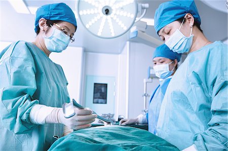 simsearch:649-09078375,k - Surgeons performing surgery on patient abdomen in maternity ward operating theatre Stock Photo - Premium Royalty-Free, Code: 649-09078369