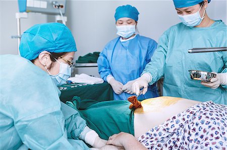reparto maternità - Surgeons swabbing patient abdomen in maternity ward operating theatre Fotografie stock - Premium Royalty-Free, Codice: 649-09078361