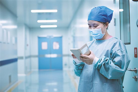 Female surgeon looking at smartphone in maternity ward operating theatre corridor Stock Photo - Premium Royalty-Free, Image code: 649-09078378