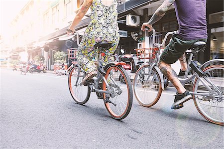 Waist down view of multi ethnic hipster couple cycling along street, Shanghai French Concession, Shanghai, China Stock Photo - Premium Royalty-Free, Code: 649-09078421