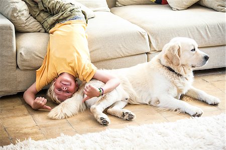 Boy lying upside down on sofa with dog Stock Photo - Premium Royalty-Free, Code: 649-09078521
