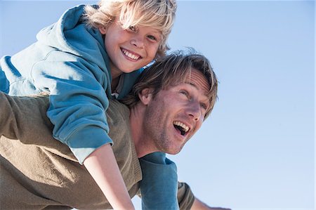 Father carrying smiling boy on back Stock Photo - Premium Royalty-Free, Code: 649-09078535