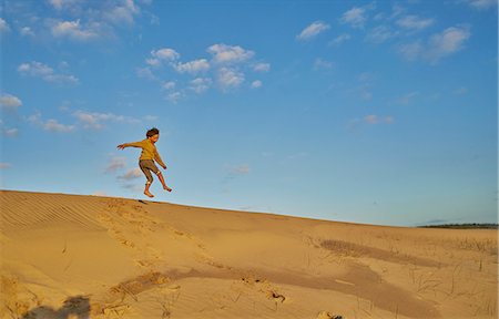 simsearch:649-07648439,k - Boy in mid air jumping down dune, Polonio, Rocha, Uruguay, South America Stock Photo - Premium Royalty-Free, Code: 649-09078609