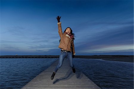 Young woman jumping on pier at dusk, Tarragona, Catalonia, Spain Photographie de stock - Premium Libres de Droits, Code: 649-09111376