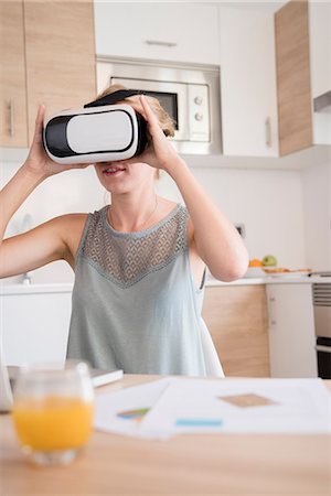 simsearch:649-08577535,k - Young woman looking through virtual reality headset at kitchen table Stock Photo - Premium Royalty-Free, Code: 649-09111392