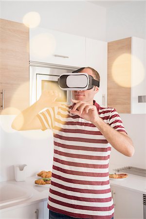 simsearch:649-08702682,k - Mature man looking through virtual reality headset in kitchen Stock Photo - Premium Royalty-Free, Code: 649-09111393