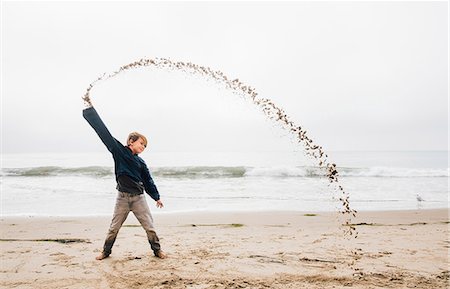 Portrait of young boy on beach, throwing sand in arch shape Photographie de stock - Premium Libres de Droits, Code: 649-09111574