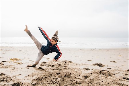 Young boy on beach, practising martial arts, leg raised in kick Stock Photo - Premium Royalty-Free, Code: 649-09111571