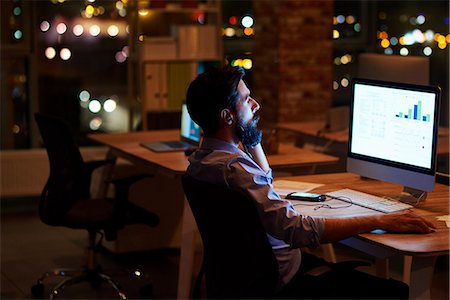 simsearch:649-09124004,k - Young businessman looking at computer on office desk at night Photographie de stock - Premium Libres de Droits, Code: 649-09124015