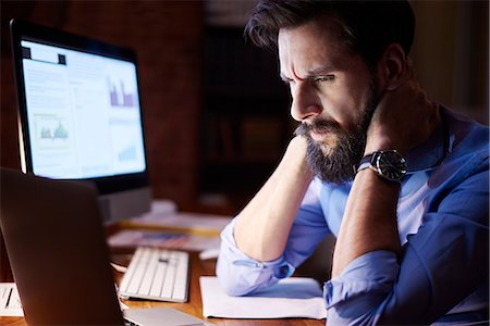 stressed guy working late - Stressed young businessman looking at laptop on office desk at night Stock Photo - Premium Royalty-Free, Code: 649-09124017