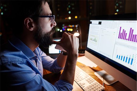 finance - Young businessman looking at computer on office desk at night Stock Photo - Premium Royalty-Free, Code: 649-09124012