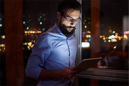 simsearch:649-09124004,k - Young businessman looking at digital tablet in office at night Photographie de stock - Premium Libres de Droits, Code: 649-09124013