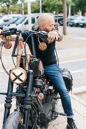 simsearch:649-09123411,k - Mature male hipster astride motorcycle, looking over his shoulder Stock Photo - Premium Royalty-Free, Code: 649-09123396