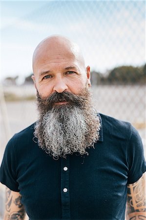 simsearch:649-09123400,k - Portrait of mature male hipster with grey beard in front of wire fence Foto de stock - Sin royalties Premium, Código: 649-09123399