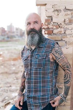 simsearch:649-09123400,k - Tattooed mature male hipster leaning against wall of demolished building Foto de stock - Sin royalties Premium, Código: 649-09123409