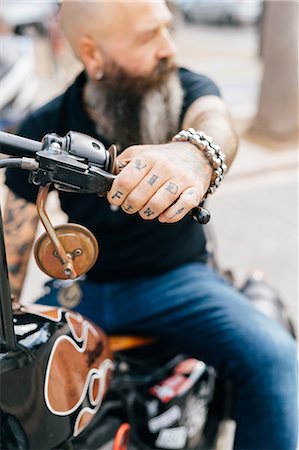 simsearch:649-09123400,k - Mature male hipster astride motorcycle, close up of tattooed hand Foto de stock - Sin royalties Premium, Código: 649-09123401