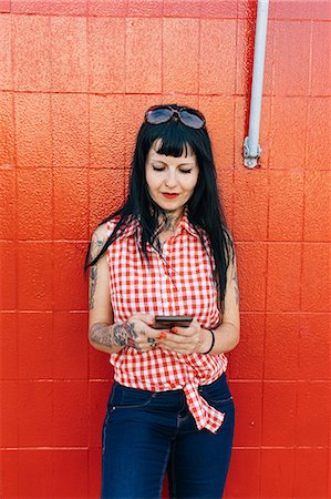 einzigartig - Mature female hipster leaning against red wall looking at smartphone Stockbilder - Premium RF Lizenzfrei, Bildnummer: 649-09123415