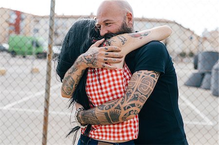 simsearch:649-09123400,k - Mature tattooed hipster couple hugging by wire fence Foto de stock - Sin royalties Premium, Código: 649-09123436